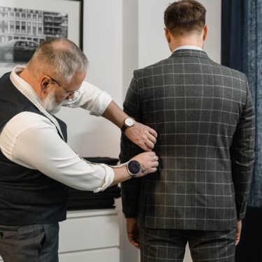 Tailor making precise adjustments to a custom suit in a professional atelier setting.